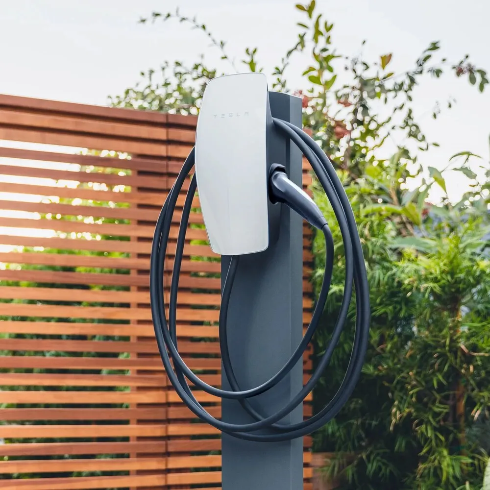 Tesla Wall Connector blanco con el cable Tipo 2 recogido, instalado en un poste de exterior